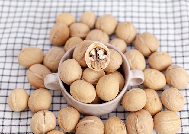 Molte noci intere in una tazza su un primo piano del tovagliolo. Alimento sano, biologico e salutare con un alto contenuto di proteine e proteine.