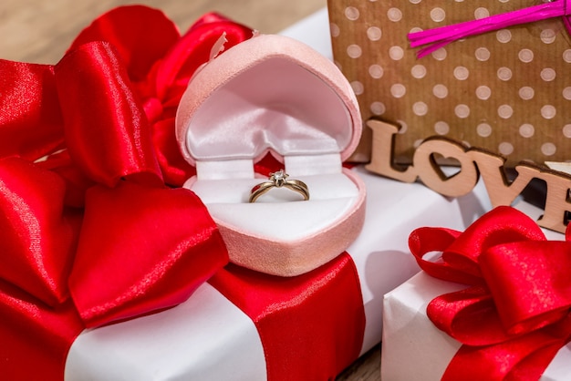 Molte scatole regalo decorate con fiocchi di nastro e scatola aperta con anello d'oro