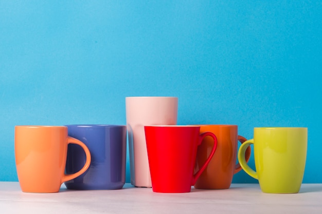 Molte tazze di caffè o tè multicolori su una priorità bassa blu. Il concetto di compagnia amichevole, famiglia numerosa, incontro di amici per una tazza di tè o caffè.