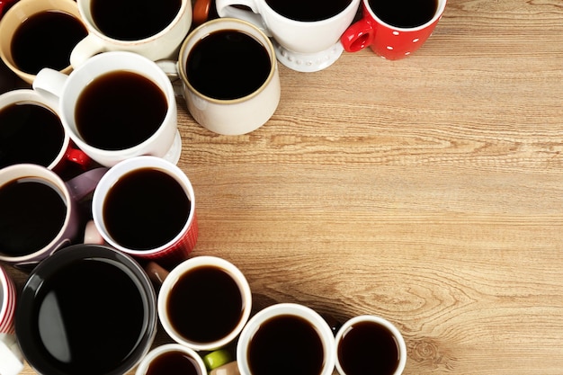 Molte tazze di caffè sulla vista del primo piano del fondo della tavola di legno