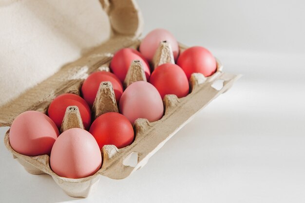 Molte uova organiche colorate nella scatola delle uova con raggi di sole. Composizioni in colori pastello.