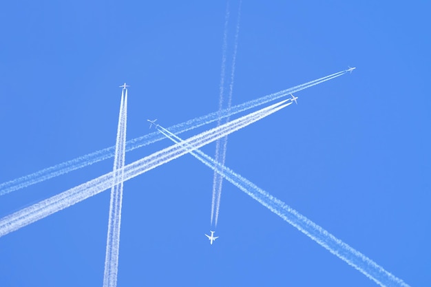 Molti aerei a reazione passeggeri distanti che volano in alta quota su un cielo azzurro chiaro lasciando dietro di sé tracce di fumo bianco di scia. Concetto di trasporto aereo occupato.