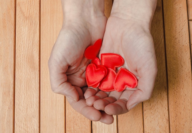 Molti cuori rossi nelle palme delle donne Fondo in legno