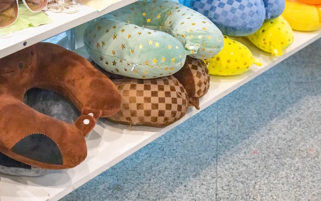 Molti cuscini colorati gonfiabili e morbidi per la comodità del collo durante il viaggio giacciono sul bancone del negozio il concetto di vendita di merci su strada