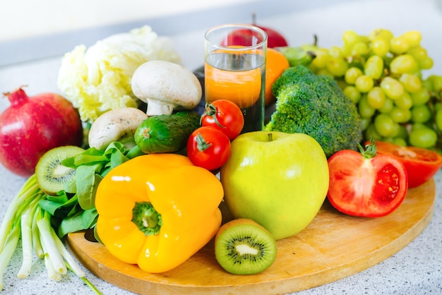 Molti diversi tipi di frutta e verdura con un bicchiere d'acqua nel mezzo