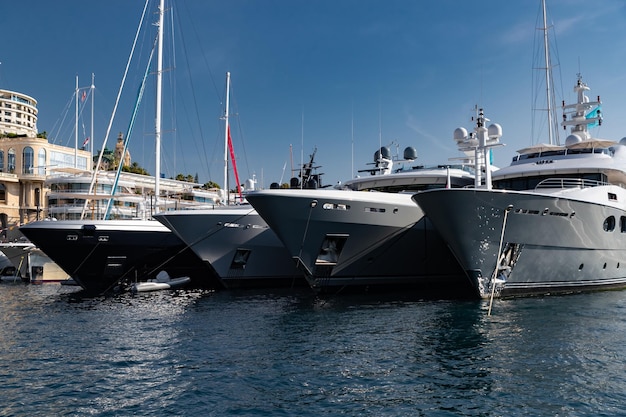 Molti enormi yacht sono nel porto di monaco in una giornata di sole la montagna di monte carlo è sullo sfondo lucido...