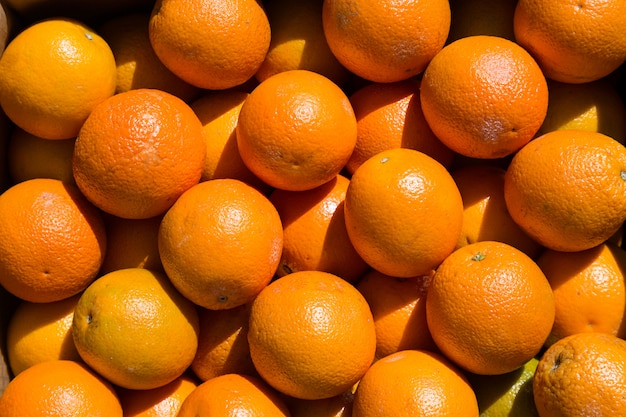 Molti frutti arancio ad un mercato durante il giorno soleggiato.