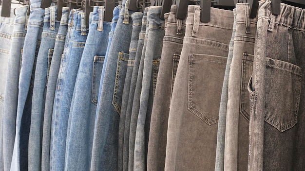 Molti jeans appesi su arack Fila di pantaloni denim jeans appesi nell'armadio concetto di acquisto vendita shopping e moda jeans