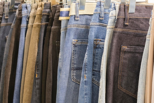 Molti jeans appesi su arack fila di pantaloni jeans denim appesi in armadio concetto di comprare vendere shopping e jeans moda
