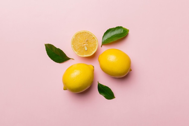 Molti limoni freschi maturi con foglie verdi su sfondo colorato vista dall'alto spazio per il testo