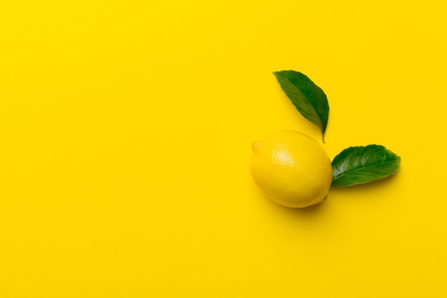 Molti limoni freschi maturi con foglie verdi su sfondo colorato vista dall'alto spazio per il testo