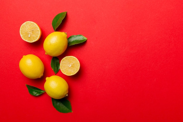 Molti limoni freschi maturi con foglie verdi su sfondo colorato vista dall'alto spazio per il testo