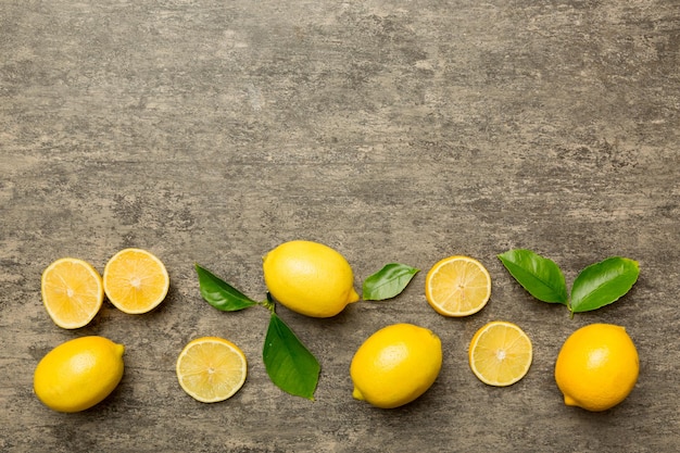 Molti limoni freschi maturi con foglie verdi su sfondo colorato vista dall'alto spazio per il testo