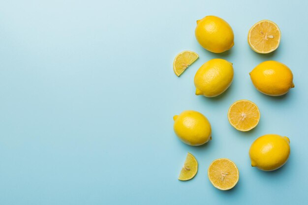 Molti limoni freschi maturi con foglie verdi su sfondo colorato vista dall'alto spazio per il testo