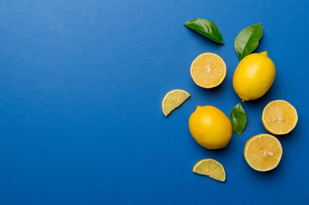 Molti limoni freschi maturi con foglie verdi su sfondo colorato vista dall'alto spazio per il testo