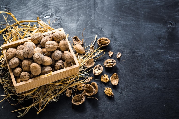 Molti noci secchi in scatola di legno su sfondo nero. Copia spazio