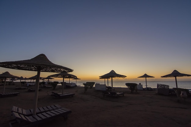 Molti ombrelloni in spiaggia durante l'alba colorata in vacanza