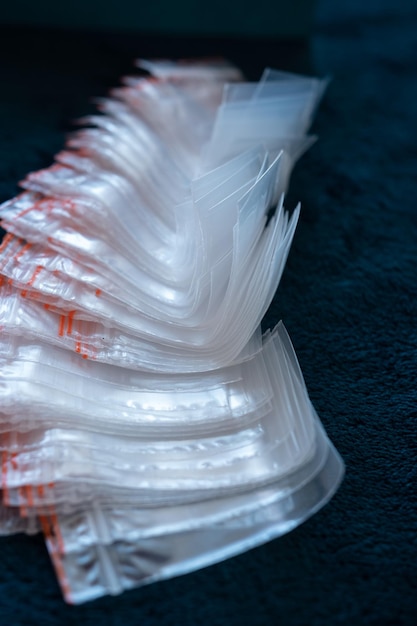 Molti piccoli sacchetti trasparenti in plastica per l'imballaggio su uno sfondo scuro e semplice Cornice verticale del primo piano