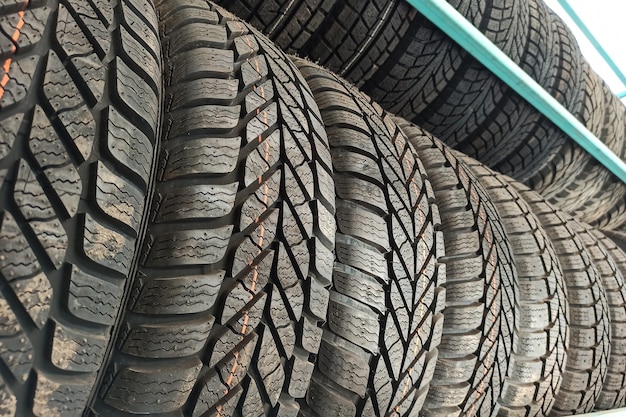 Molti pneumatici per auto in gomma nera sullo scaffale del negozio in vendita.