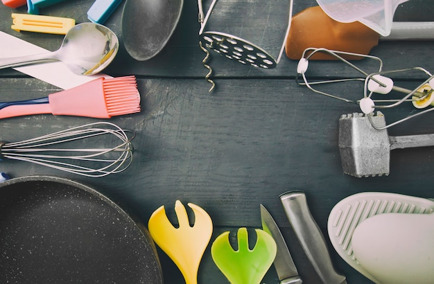 Molti utensili da cucina diversi sul tavolo di legno