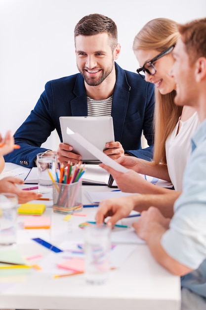 Momenti di lavoro. Gruppo di uomini d'affari in abbigliamento casual intelligente seduti insieme al tavolo e sorridenti