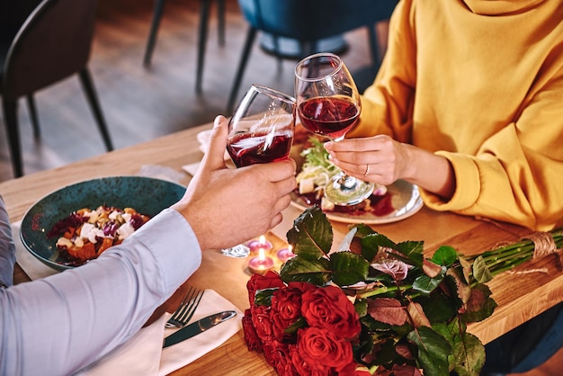 Momenti felici primo piano delle coppie che tengono vino rosso nel ristorante