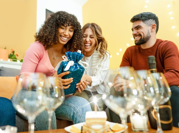 Momento di buon compleanno con persone reali multirazziali a casa che ridono celebrando con champagne