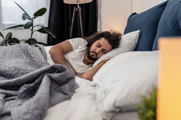 Momento di dormire. Un bell'uomo barbuto che dorme nel suo letto mentre è a casa