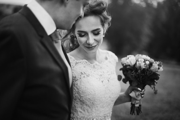 Momento di matrimonio romantico coppia di sposi novelli che si abbracciano all'aperto con bouquet giovane ritratto di famiglia bella sposa e bello sposo innamorato