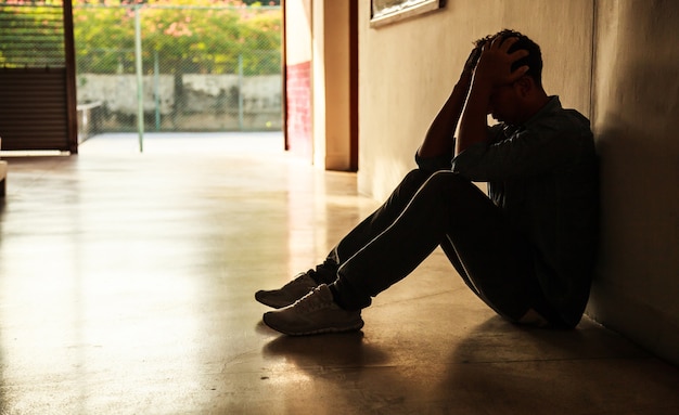 Momento emotivo: uomo seduto tenendo la testa tra le mani, stressato giovane maschio triste avendo mentale