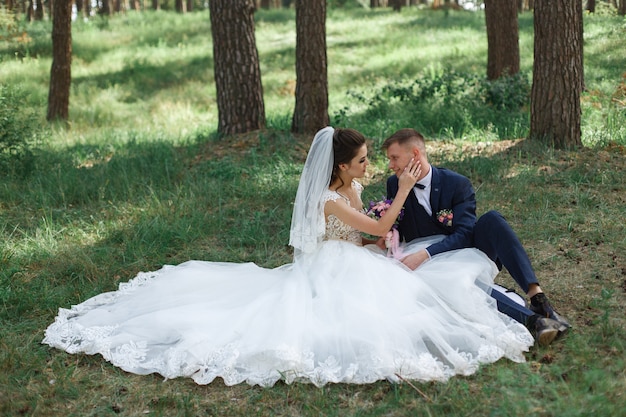 Momento romantico del matrimonio. Giovani sposi felici che abbracciano all'aperto nel parco verde. Bello ritratto degli sposi all'aperto.