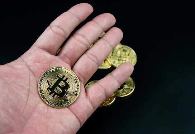 Moneta Bitcoin posta sulla mano su sfondo nero