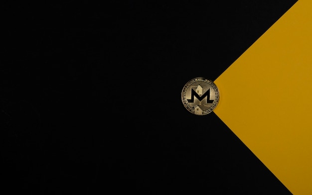 Moneta d'oro Monero su sfondo nero e giallo come criptovaluta a busta e investimento crittografico