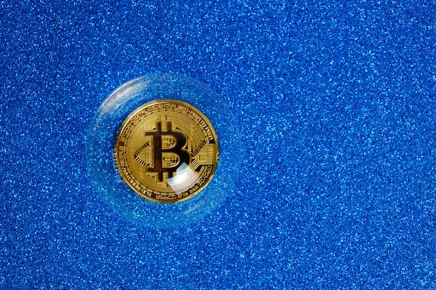 Moneta di criptovaluta Bitcoin in una bolla di sapone su sfondo blu.