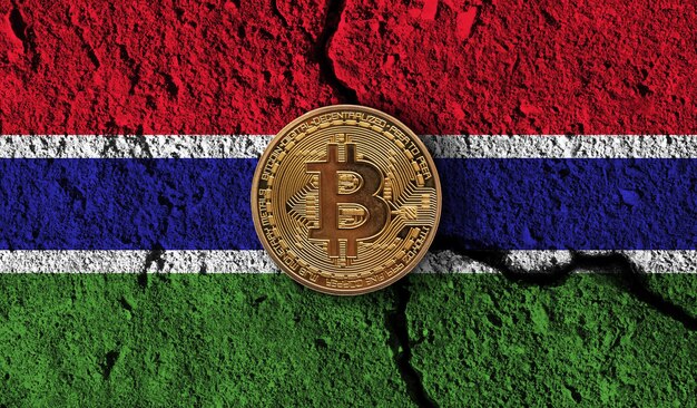 Moneta in criptovaluta Bitcoin con restrizioni crittografiche della bandiera del gambia incrinate