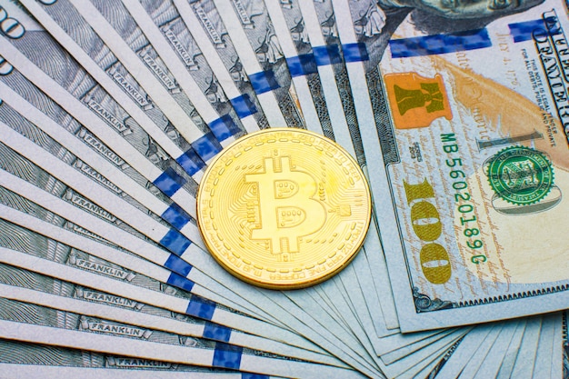 Monete Bitcoin BTC su sfondo di banconote cento dollari