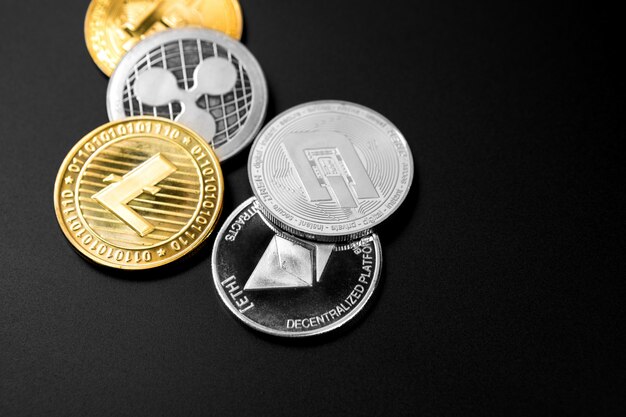 Monete d'argento e d'oro con il simbolo bitcoin, ripple ed ethereum su legno.