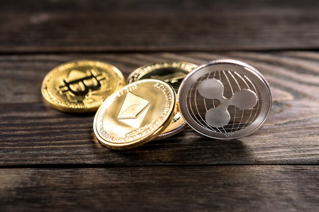 Monete d&#39;argento e d&#39;oro con simbolo bitcoin, ripple ed ethereum