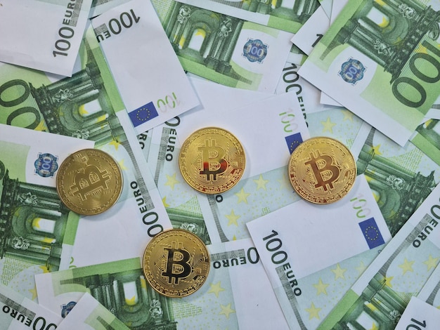 Monete d'oro bitcoin di criptovaluta su banconote da 100 euro