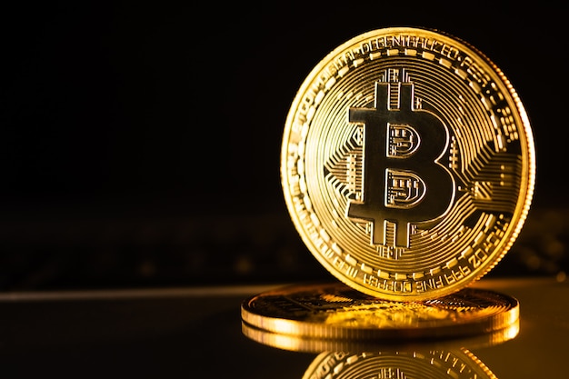 Monete d'oro con il simbolo bitcoin su sfondo nero.