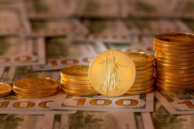 Monete d'oro impilate su nuove banconote da 100 dollari
