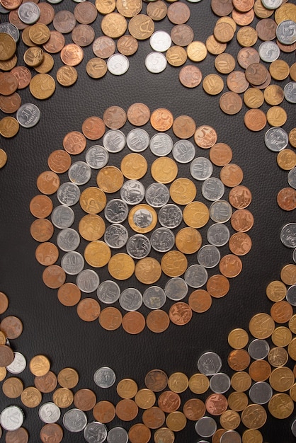 Monete, monete brasiliane di vario valore â€‹â€spalmate su una superficie in pelle nera, vista dall'alto.