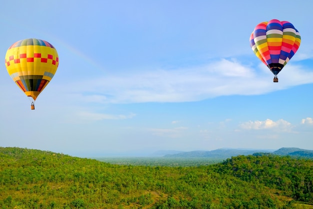 Mongolfiera che galleggia nel cielo vicino ad un arcobaleno sopra le montagne.