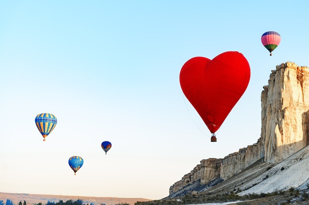 Mongolfiera rossa a forma di cuore che vola nel cielo limpido