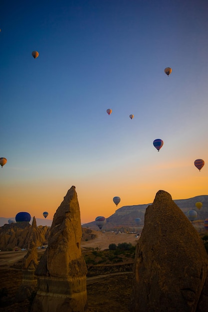 Mongolfiere sorvolano paesaggi rocciosi in Cappadocia