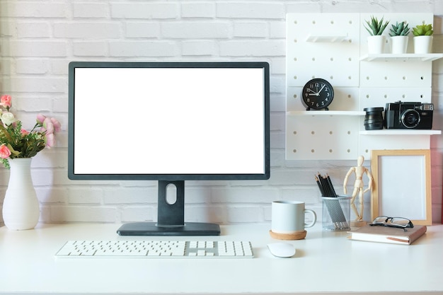 Monitor del computer vuoto e forniture per ufficio sul tavolo bianco nel posto di lavoro moderno