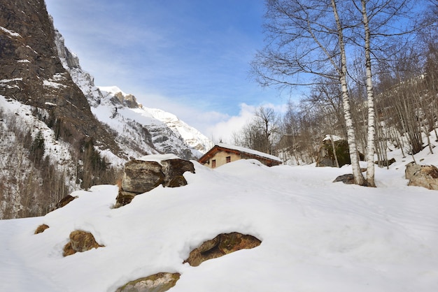 Montagna alpina nella neve con uno chalet sepolto nella neve