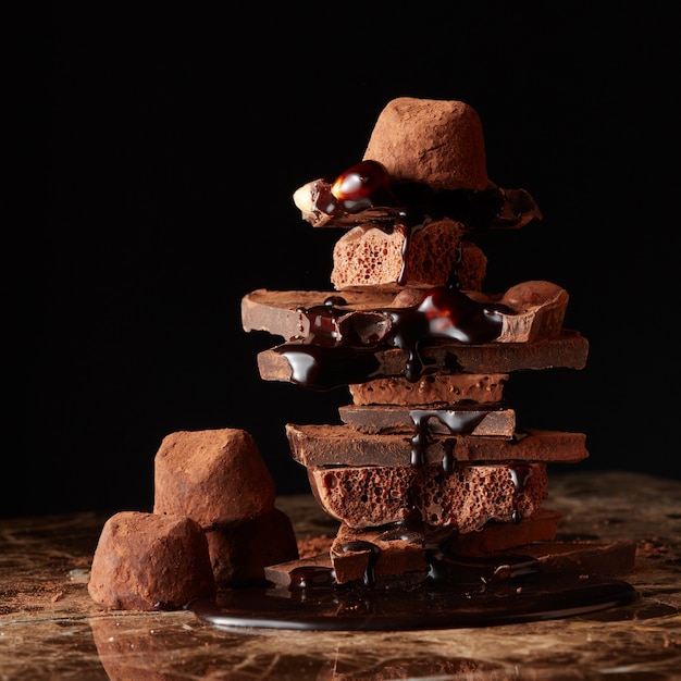 Montagna di pezzi di cioccolato fondente con gocce di cioccolato su una superficie di marmo