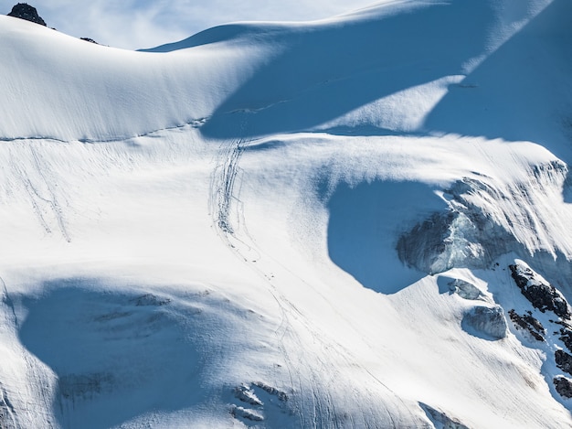 Montagna innevata all'aperto in inverno. Paesaggio di cime innevate con tracce di pietre che cadono. Montagne catturate nella neve, luogo ideale per gli sport estremi invernali.