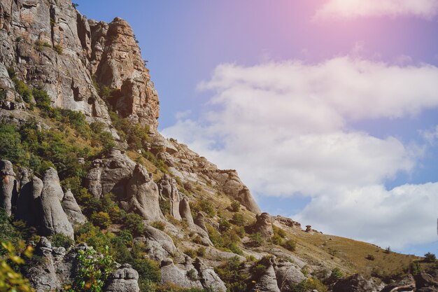 Montagna rocciosa con alberi contro il cielo con nuvole colorate